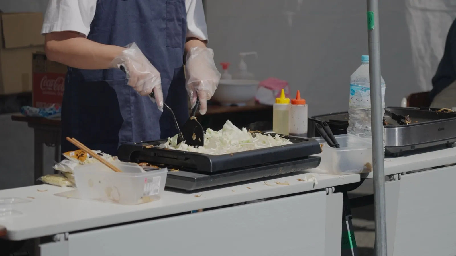 模擬店で学生が鉄板で焼きそばを調理している様子